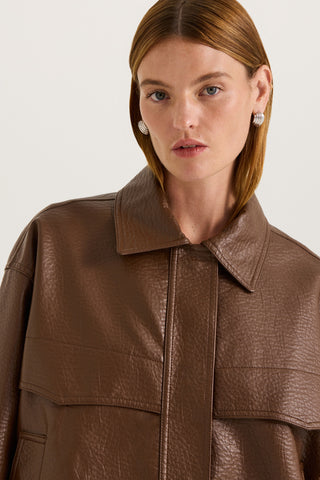 Close up view of a model wearing a brown leather effect jacket on a white background