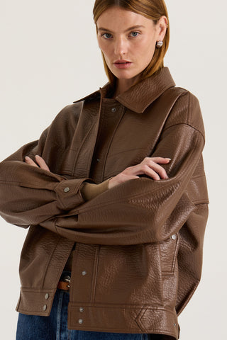 Model wearing a brown leather effect jacket on a white background