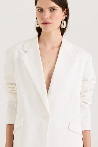 Close up of a model wearing a white blazer a white background