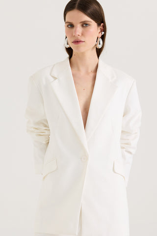 Close up of a model wearing a white blazer a white background