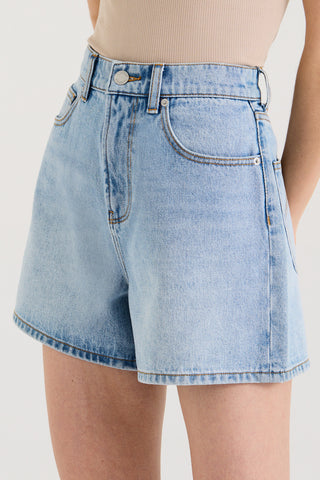 Close up view model wearing light blue denim shorts on a white background