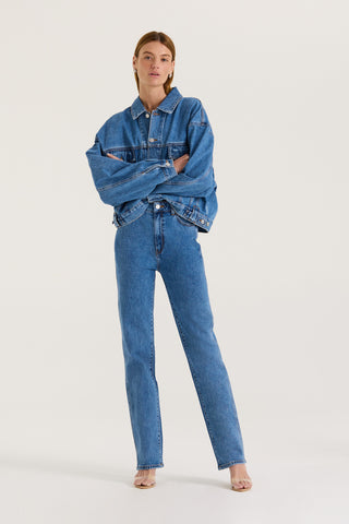 Model wearing an indigo denim jacket and indigo wash high rise, straight leg jeans on a white background