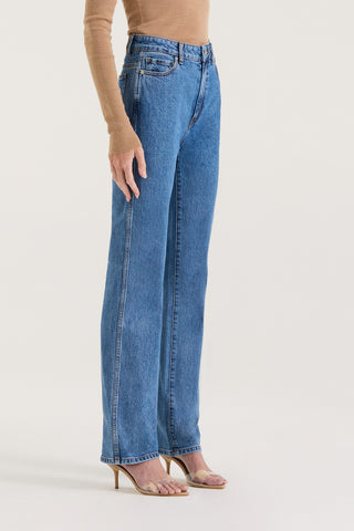 Model wearing indigo straight leg, high rise jeans on a white background