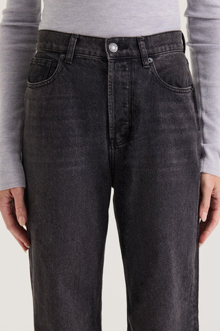 Close up view of models waistband in black wash Jeans, with a high rise and straight leg, on white background.